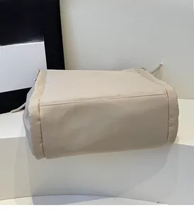 Detail view of reinforced stitching and durable canvas fabric on a beige tote bag base