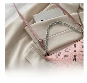 Detailed close-up of pink bucket bag with gold chain and letter print pattern