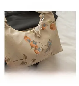 Detail of silk texture beige shoulder bag with bird and persimmon embroidery