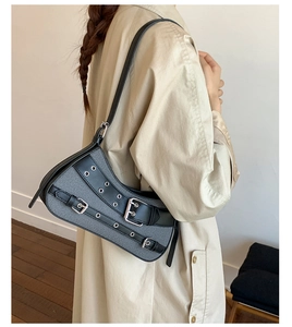 Detail of vintage punk denim underarm bag featuring silver eyelets and leather trim