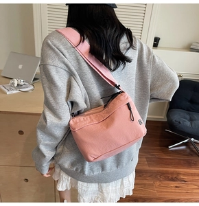 Dettaglio della borsa a tracolla in nylon rosa con doppia cerniera e ampia tracolla in tessuto