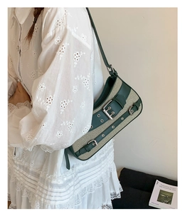 Detail of vintage beige canvas and green leather shoulder bag with metal buckles