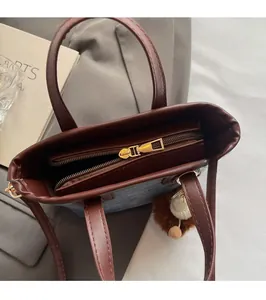 Close-up of contrast leather trim, smooth zipper, and gray fabric texture of a bucket bag