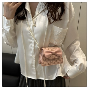 Pink mini crossbody bag with monogram print, leather bow, and pearl shoulder strap detail