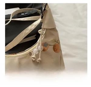 Detailed close-up of premium metal zipper and fruit embroidery on silk handbag