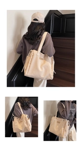 Detail of beige canvas tote bag with drawstring side folds and rectangle leather logo patch