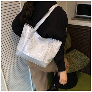 Silver-grey tote bag with butterfly print shown on shoulder in office setting
