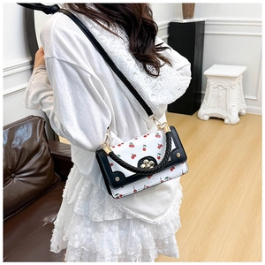 Detail of white crossbody bag with red cherry prints and black braided handle for women