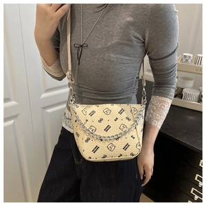 On-body view of cream shoulder bag with cartoon bear print and silver metal chain