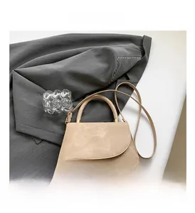 Detail view of the beige suede shoulder bag with gold hardware and curved flap design