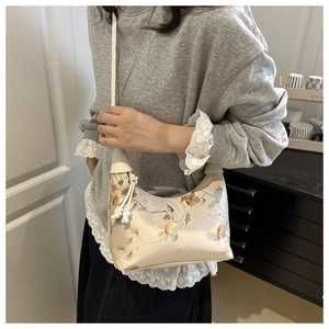 Cream hobo bag with flower and bird embroidery shown on model for casual daily look