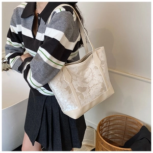 Close-up of cream tote bag featuring butterfly print and embossed FASHION lettering detail