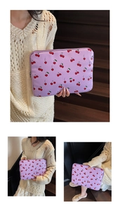 Detail of purple laptop sleeve with cherry print featuring a zip closure and soft fabric