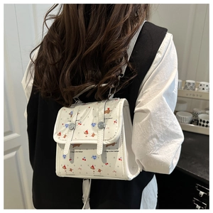Detailansicht eines weißen Mini-Rucksacks mit Hundemustern, der von einem Model getragen wird