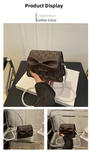 Detail of brown mini crossbody bag with M-pattern, bow decoration and pearl chain strap