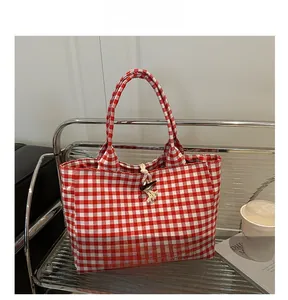 Detail of red and white checkered canvas tote bag featuring horn buckle closure