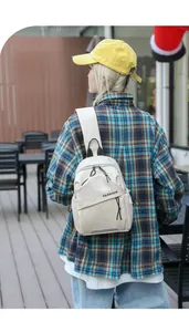 Outdoor lifestyle shot of a cream beige mini nylon fashion chest bag with adjustable strap