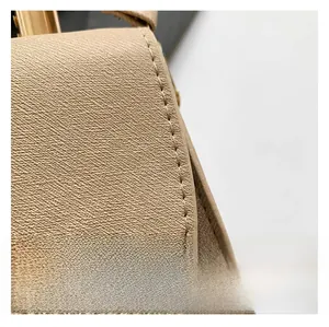 Close-up of beige crossgrain leather shoulder bag with precision stitching detail