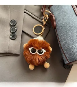 Close-up of a brown fluffy plush charm with white sunglasses on a blue crossbody bag