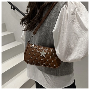 Detail of a brown quilted crossbody bag with rhinestone star and silver metal rivets