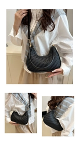 Detail view of black woven leather crescent bag with chevron weave and golden hardware