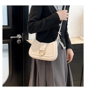 Detail of cream saddle shoulder bag with matte leather and a gold D-shaped metal buckle