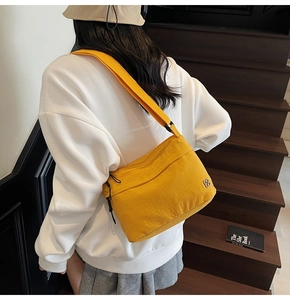 Dettaglio borsa a tracolla in nylon giallo acceso con emblema floreale argento su modella