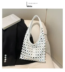 Detail of white hobo bag with silver metallic studs and rivets on beige leather surface