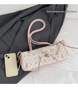 Pink printed shoulder bag with bow and heart detail next to a smartphone for size scale