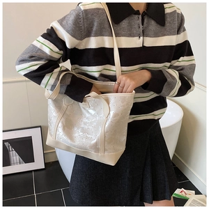 Chic cream tote bag with subtle shimmer styled with a striped polo sweater and pleated skirt