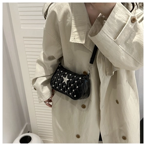 Black quilted crossbody bag featuring silver star and rhinestone studs on a chic model