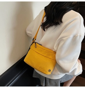 Dettaglio macro di una borsa a tracolla in nylon giallo con logo in metallo