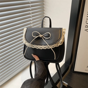 Mini black backpack for women featuring lace trim and a cream bow on the front