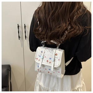 Nahaufnahme eines weißen Mini-Rucksacks mit süßen Comic-Mustern auf dem Rücken eines Modells