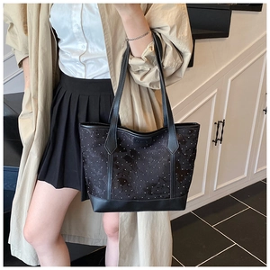 Detail of black tote bag with embossed texture and Fashion label on the shoulder strap