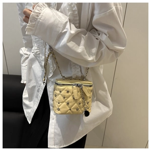 Close-up detail of a yellow quilted mini box bag with metallic studs and a chain strap