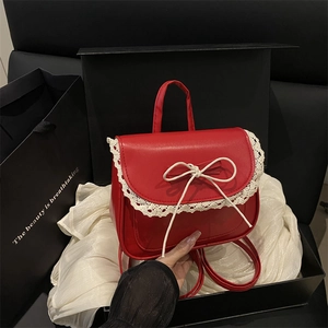 Sweet red leather shoulder bag with white lace trim and bow on black silk background