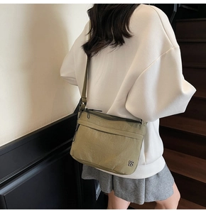 Dettaglio della borsa a tracolla in nylon verde oliva con cerniere e logo a forma di fiore