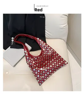 Detail of red leather bucket bag with silver metal rivets and wide shoulder strap
