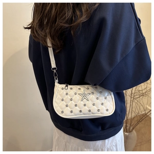 Gros plan du sac bandoulière matelassé blanc orné d'étoiles et rivets brillants