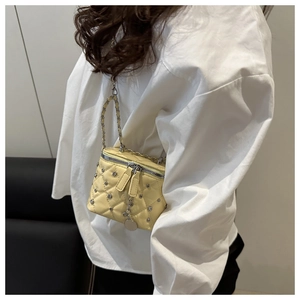 Close-up view of a stylish yellow quilted chain crossbody box bag worn with a white shirt