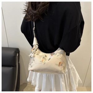 Detail of elegant beige shoulder bag featuring floral embroidery and tassel drawstring