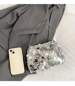 Close-up of silver sequin mini crossbody bag on grey blazer with phone for scale