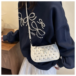 Close-up of white patent leather square bag with quilted rhinestones and star detail