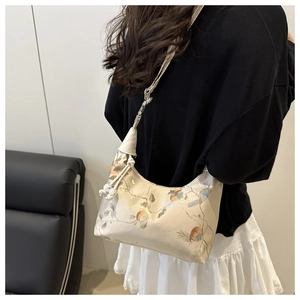 Detail of floral patterned half-moon crossbody bag shown on model with shoulder strap