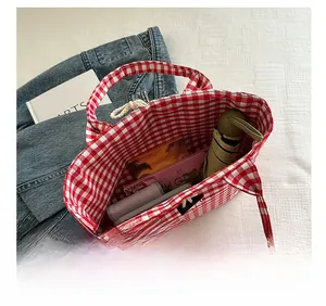 Detail showing the spacious interior of a large red and white checkered canvas tote bag