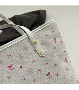 Détail du cabas blanc avec imprimé fleuri rose et rivets métalliques dorés sur l'anse