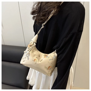 Close-up of cream embroidered crossbody bag with floral patterns and leather strap