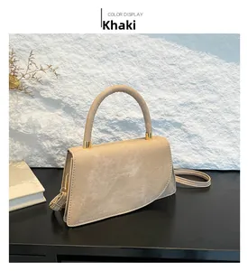 Detail view of khaki suede tote bag featuring a curved top handle and gold metal hardware