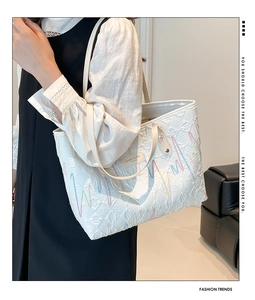 Detailed view of a white embroidered canvas tote bag worn elegantly on the shoulder.
